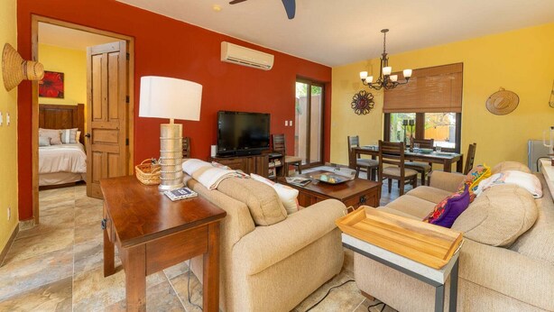 A living room with a sofa, TV, dining table, and ceiling fan. - Wonderful Home Next to the Community Pool ( Loreto)