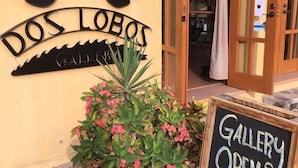 A building entrance with a sign reading 'DOS LOBOS' and a chalkboard sign indicating 'GALLERY OPEN MON-FRI 3-9 PM'. - Wonderful Home Next to the Community Pool (  Loreto)