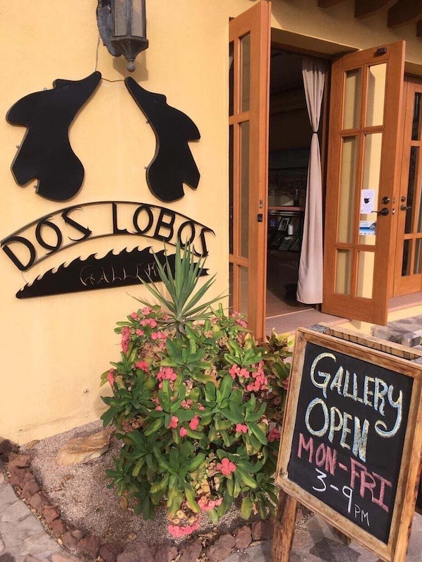 A building entrance with a sign reading 'DOS LOBOS' and a chalkboard sign indicating 'GALLERY OPEN MON-FRI 3-9 PM'. - Wonderful Home Next to the Community Pool (  Loreto)