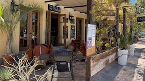 A covered outdoor seating area with tables and chairs, a sign reading "Le Bistro," and potted plants. - Wonderful Home Next to the Community Pool ( Loreto)