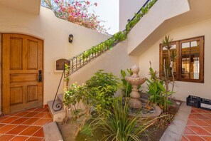 A courtyard with a wooden door, a staircase with greenery, a stone fountain, and a window with a view. - Amazing Home a few Steps to the Beach (  Loreto)