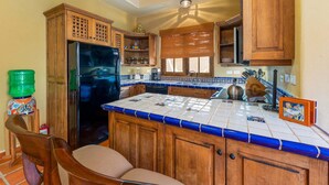 A kitchen with wooden cabinets, a refrigerator, a tiled backsplash, and a window with blinds. - Amazing Home a few Steps to the Beach (  Loreto)