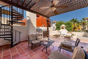 Eine Terrasse mit Gartenmöbeln, einem Grill und einer Treppe.