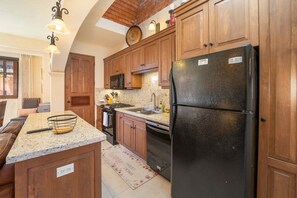 Eine Küche mit Holzschränken, einem schwarzen Kühlschrank, Granitarbeitsplatten, einer Mikrowelle und einem Herd.