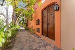 A stone-paved pathway leading to a building with a wooden door and a wall-mounted light fixture. - Stunning Home - Amazing Mountain Views (  Loreto)