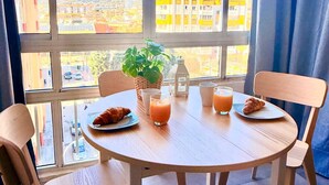 A dining table with chairs, a plant, and breakfast items in a room with large windows. - Studio with Pool in Hércules - Gamonal (Benalmádena)