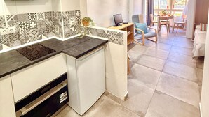 A modern kitchen with white cabinets, a patterned backsplash, and a dining area with a table and chairs. - Studio with Pool in Hércules - Gamonal (Benalmádena)