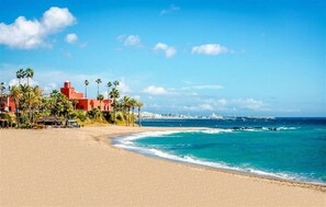 A beach with a building, palm trees, and the ocean. - Studio with Pool in Hércules - Gamonal (Benalmádena)
