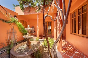 An outdoor courtyard with a fountain, a wooden fence, and a door leading to a building. - Water and Mountain Views-steps to Beach and Inn (  Loreto)