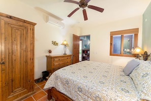 Un dormitorio con cama, armario de madera, ventilador de techo y ventana con persianas.