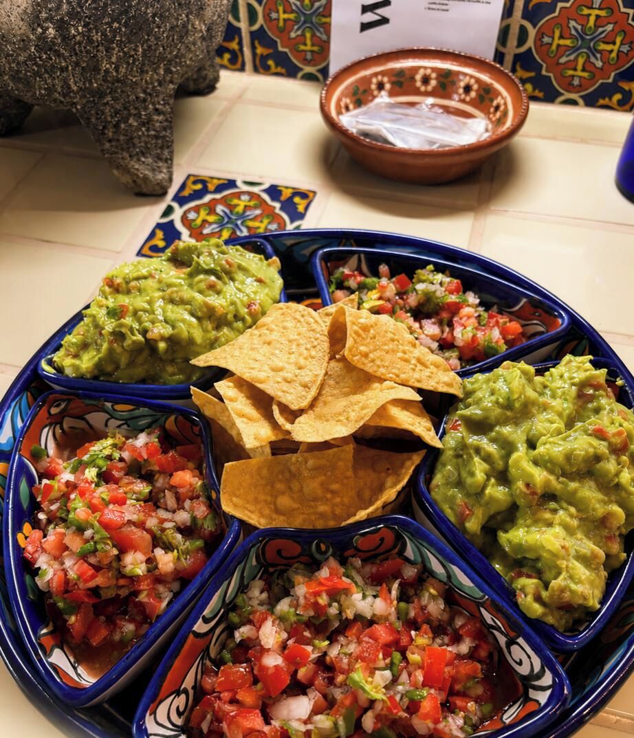 Une assiette avec trois sortes de trempettes et des chips de tortillas.