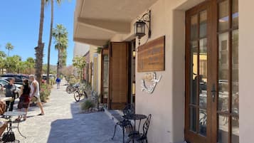 Un edificio con entrada empedrada en piedra, puerta de madera y un cartel.