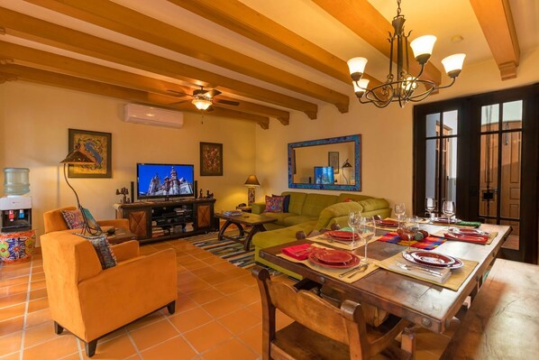 A living room with a TV, sofa, dining table set, and a large mirror. - Enchanting Loreto Bay Home, Just Steps to Pool. Bikes Available (Loreto Bay)