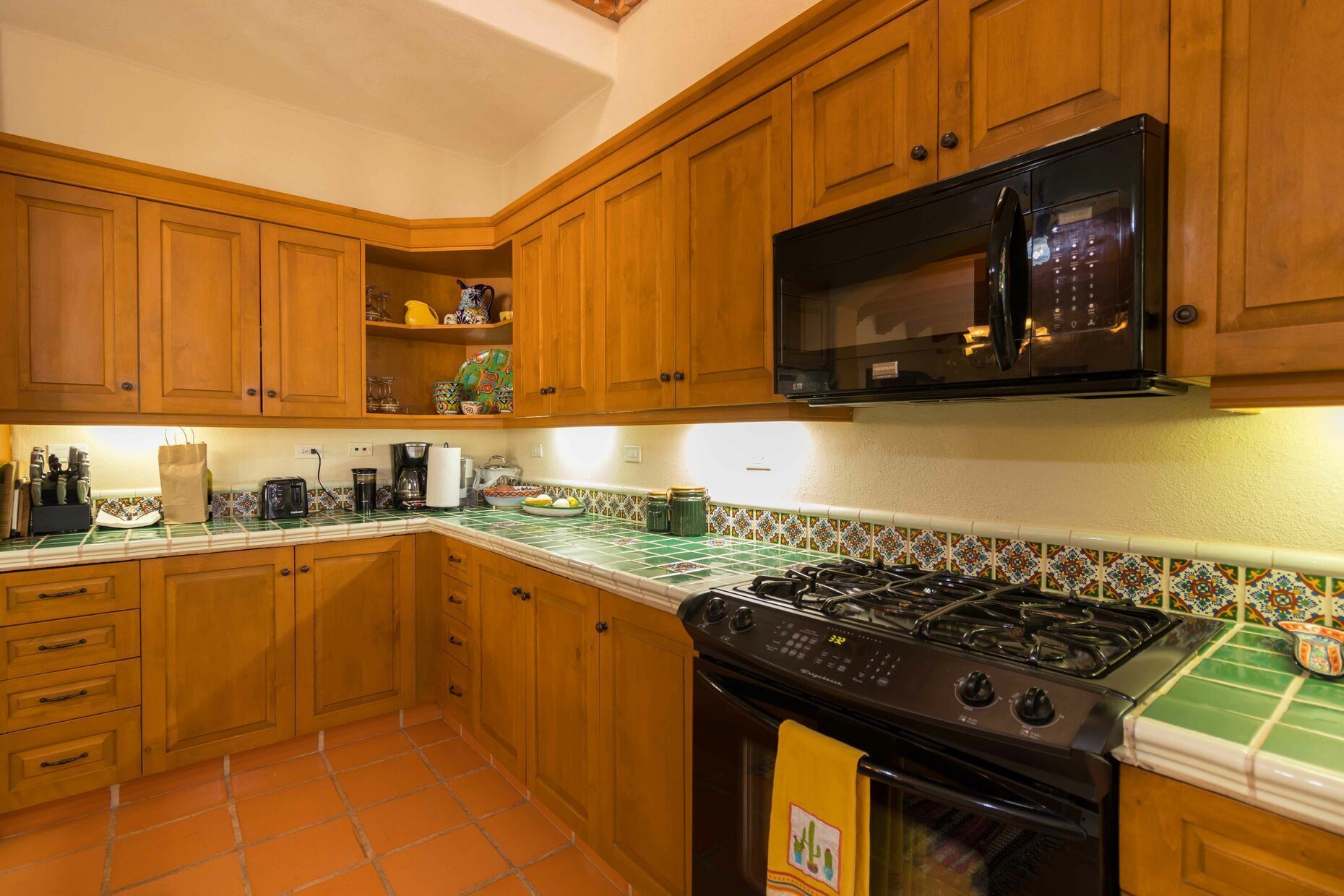 Una cucina con mobili in legno, un fornello a gas, un forno a microonde e una parete rivestita di piastrelle.