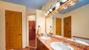 Un baño con dos lavamanos, una ducha y un espejo grande.