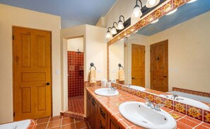 Un baño con dos lavamanos, una ducha y un espejo grande.