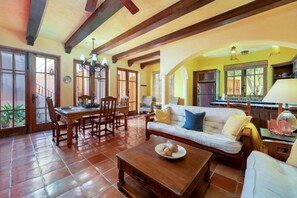 Ampla sala de estar com mesa de jantar, sofá e cozinha ao fundo.