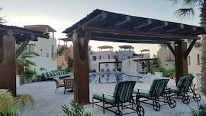 A pool area with lounge chairs, a pergola, and a view of buildings in the background. - Charming Home in Loreto Bay, Steps From the Golf Course and From Coffee Shop (  Loreto)