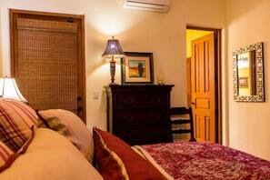 Un dormitorio con cama, cómoda, lámpara y un cuadro enmarcado.