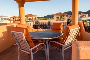 Una terraza con una mesa redonda y cuatro sillas, con vistas a una zona residencial con casas y montañas.