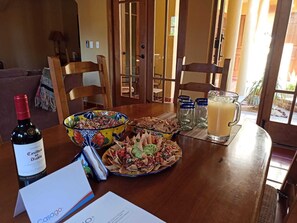 A dining table with a bottle of Casillero del Diablo wine, a colorful bowl, a plate of nachos, and a glass of lemonade. - Spectacular Home Located Steps From Lap Pool With Great Patio (  Loreto)