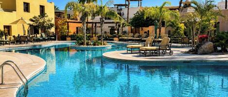 A pool area with lounge chairs and palm trees.