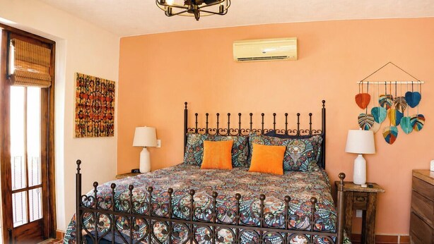 Un dormitorio con una colcha estampada, un tapiz decorativo y una lámpara en el techo.