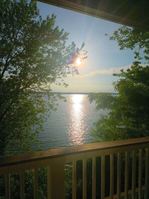 A view of a lake with trees in the foreground and a clear sky.