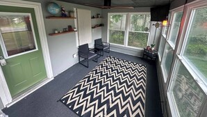 A room with a chevron-patterned rug, a green door, a globe, and a shelf with plants. - Cozy 2-bedroom house in tranquil Chesterton with AC (Chesterton)
