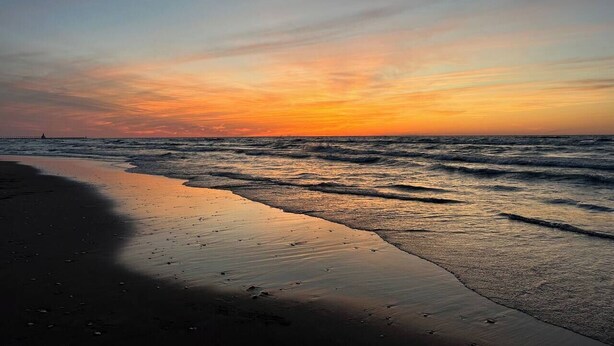 A beach at sunset with waves, a visible shoreline, and a distant boat. - Cozy 2-bedroom house in tranquil Chesterton with AC (Chesterton)