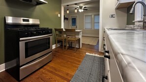 A modern kitchen with stainless steel appliances, a dining area with wooden chairs, and a view to a living space. - Cozy 2-bedroom house in tranquil Chesterton with AC (Chesterton)