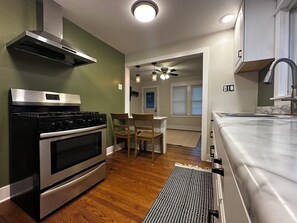A modern kitchen with stainless steel appliances, a dining area with wooden chairs, and a view to a living space. - Cozy 2-bedroom house in tranquil Chesterton with AC (Chesterton)