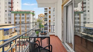 A balcony with a table, chairs, and a potted plant. - Apartment 40 Meters from the Beach with Balconies, Sea View, and Wi-Fi (Quarteira)