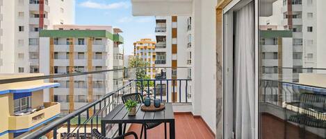 Un balcon avec une table, des chaises et un pot de fleurs.