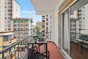 Een balkon met een tafel, stoelen en een bloempot.