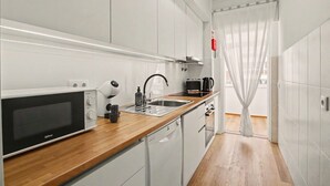 A modern kitchen with a microwave, sink, and coffee maker. - Apartment 40 Meters from the Beach with Balconies, Sea View, and Wi-Fi (Quarteira)