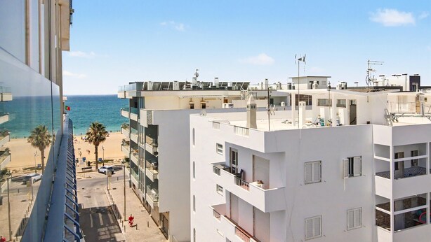 A multi-story building with balconies overlooking a beach. - Apartment 40 Meters from the Beach with Balconies, Sea View, and Wi-Fi (Quarteira)