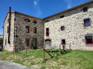 Um edifício de pedra com várias janelas e uma porta, rodeado por um espaço gramado.