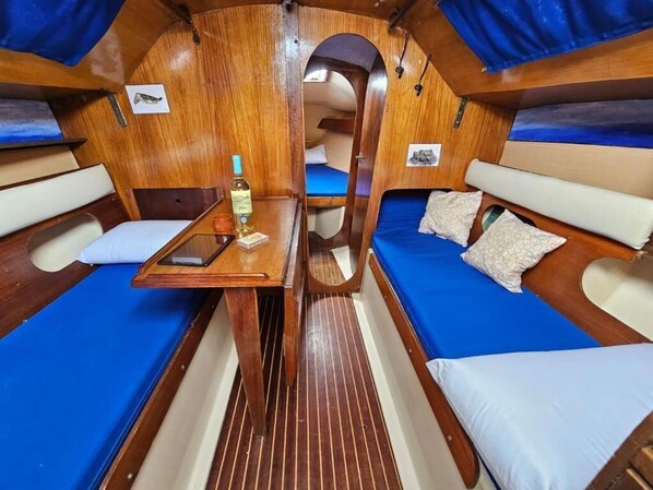 A cabin with a central table, two beds with pillows, and a small window.