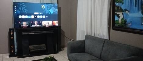Una sala de estar con un televisor de pantalla plana, un sofá gris, una mesa de centro y un cuadro en la pared.
