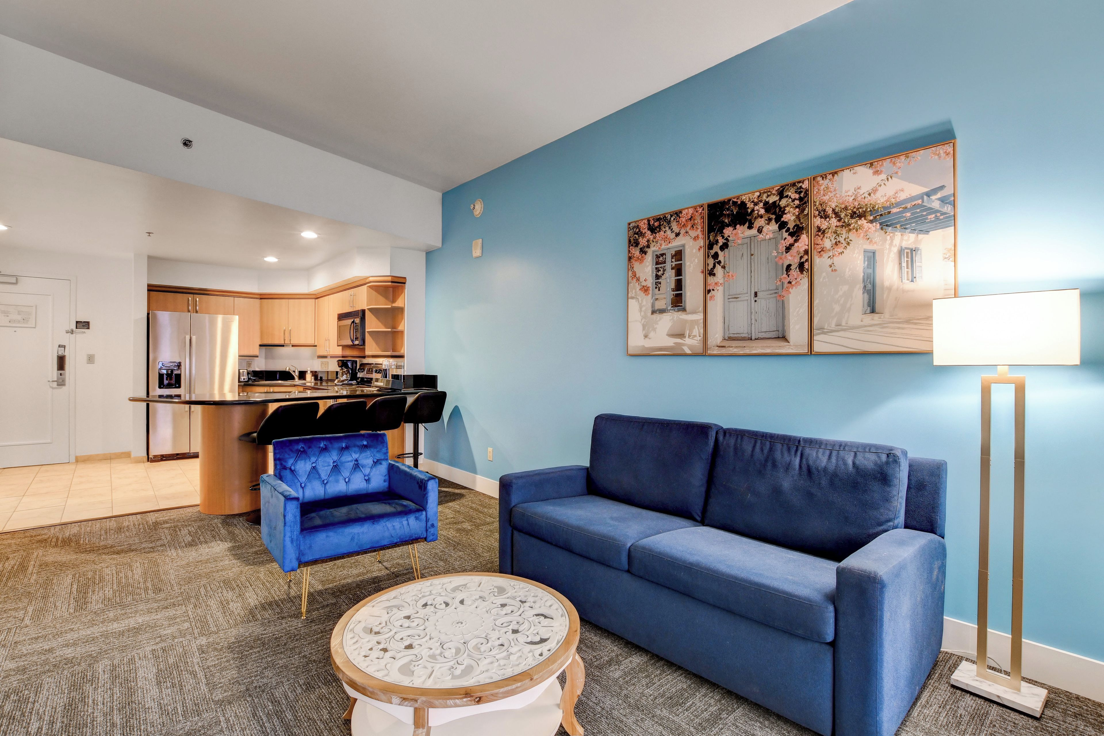 A modern living room with a blue sofa, a blue armchair, and a round coffee table.