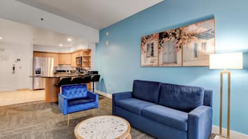 A modern living room with a blue sofa, a blue armchair, and a round coffee table.