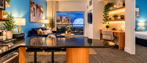 Ein modernes Hotelzimmer mit Barbereich, Sitzgelegenheiten und Blick auf die Stadt.