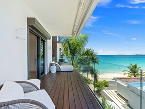 A balcony with a wooden floor, a white wall, and a view of the beach. - Spectacular Beachfront Suite in Simpson Bay (Simpson Bay)