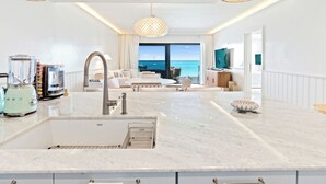 Eine moderne Küche mit einer großen Kochinsel, einem eingebauten Backofen und Meerblick.