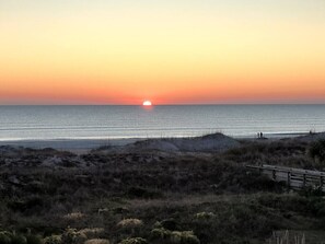 A sunset over a beach with a wooden boardwalk leading to the water. - Seaside Escape- Holiday by the sea + private beach (St. Augustine Beach)