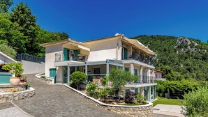 Una casa a due piani con un balcone, un vialetto in pietra e vista su una montagna.