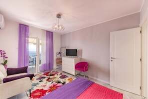 Ein Schlafzimmer mit Bett, Fernseher, Kommode, Stuhl und Tür.