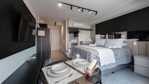 Ett modernt hotellrum med en säng, sängbord, ett skrivbord med en stol och en spegel.
