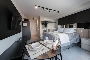 Ein modernes Hotelzimmer mit Bett, Nachttischen, einem Schreibtisch mit Stuhl und einem Spiegel.